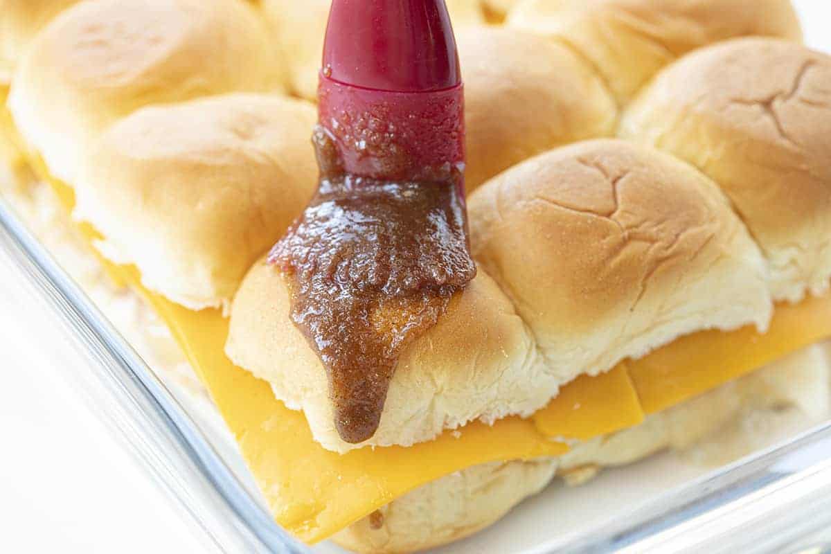 Sweet and scrumptious as apple pie with just the smallest hint of something different. The cheddar seems to lose its potent flavor and perfectly compliment the apple and cinnamon! Apple Pie Cheddar Sliders, Apple Pie Sliders, Dessert Sliders, Apple Cheese Sliders, Sliders Recipe, Recipes, iambaker, i am baker Drizzling Sauce over Apple Cheddar Sliders Before They Are Baked