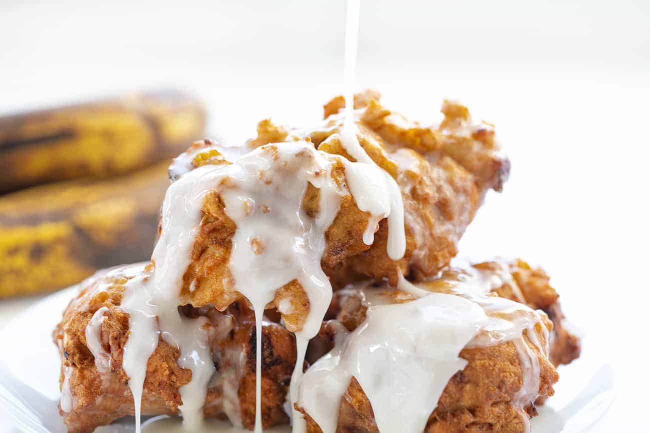 Banana Fritters are made with cakey batter, fried to perfection and loaded with bananas, all topped off with a sweet glaze. banana fritters, homemade fritters, fritters recipes, i am baker, iambaker, homemade glaze Pouring Glaze over Banana Fritters