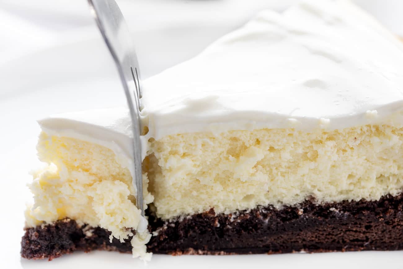 Side View of Brownie Bottom Cheesecake with Fork Inserted and Removing the Tip