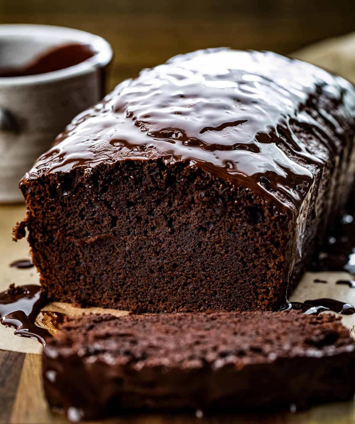 Brownie Bread is a loaf of fudgy chocolate bread that is like a brownie but cut and served like a slice of bread. Then, milk chocolate ganache gives the loaf even more chocolate flavor! It is a quick bread that will quickly be gone, for sure! This delicious treat or dessert will satisfy your sweet tooth and chocolate craving. Close up of the inside of Brownie Bread Sitting on a Cutting Board.