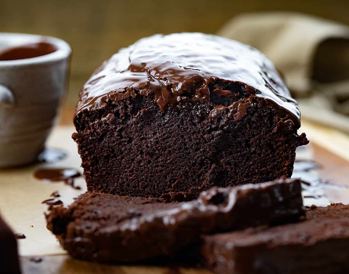 Brownie Bread is a loaf of fudgy chocolate bread that is like a brownie but cut and served like a slice of bread. Then, milk chocolate ganache gives the loaf even more chocolate flavor! It is a quick bread that will quickly be gone, for sure! This delicious treat or dessert will satisfy your sweet tooth and chocolate craving. Close up of the inside of Brownie Bread Sitting on a Cutting Board.