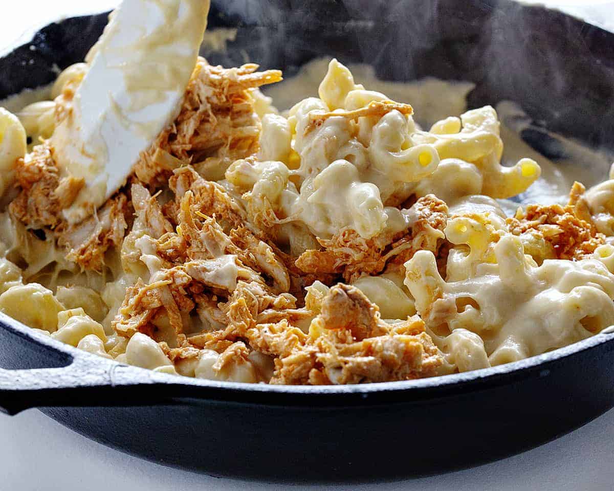 Buffalo Chicken Macaroni and Cheese is a macaroni and cheese that even adults will crave! It's buffalo chicken and cheesy noodles make for a satisfying and addicting dish! homemade macaroni and cheese, buffalo chicken macaroni and cheese, homemade buffalo sauce, home made ranch dressing, rotisserie chicken, iambaker, dinner recipes Adding buffalo chicken for Buffalo Chicken Macaroni and Cheese