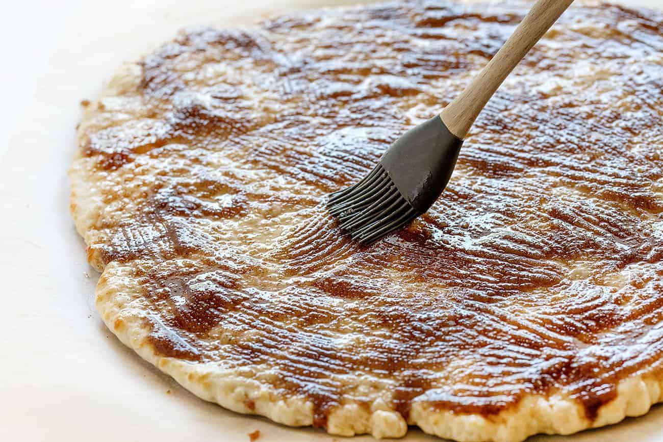 This recipe has been TESTED and PERFECTED! A glorious cinnamon-sugar dessert pizza covered in the best sweet glaze. A fan favorite! cactus bread, copycat cactus bread, dessert pizza, crispy cinnamon dessert, dessert, baking, recipes, iambaker Spreading butter and cinnamon mixture over pizza dough for Cactus Bread