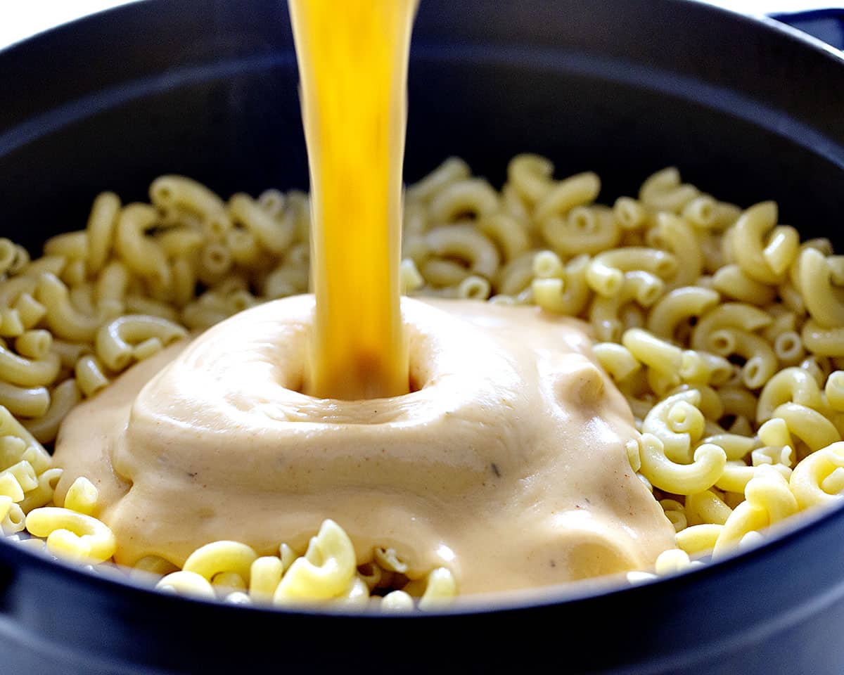 Cajun Chicken Macaroni and Cheese is a hearty, spicy, cheesy dish that will have you and your guests reaching for seconds! Cajun chicken macaroni and cheese, iambaker, dinner recipes, macaroni and cheese, homemade macaroni and cheese, cajun seasoning, homemade cajun seasoning, dinner, cajun chicken Pouring Cheese into Cajun Chicken Macaroni and Cheese