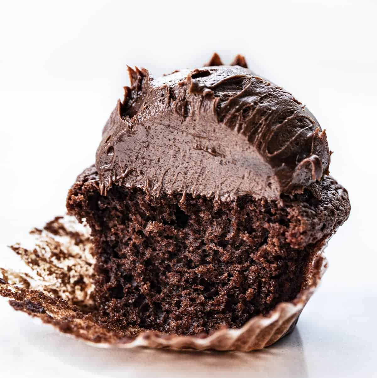 Chocolate Brownie Cupcakes are delectable chocolate cupcakes with a fine crumb and smooth texture, topped with homemade chocolate brownie frosting. chocolate brownie cupcake, chocolate cupcakes, brownie cupcakes, cupcakes recipes, homemade frosting, chocolate frosting, brownie frosting, iambaker, i am baker, baking, cupcakes Chocolate Brownie Cupcake Cut Into Showing Soft Texture Inside