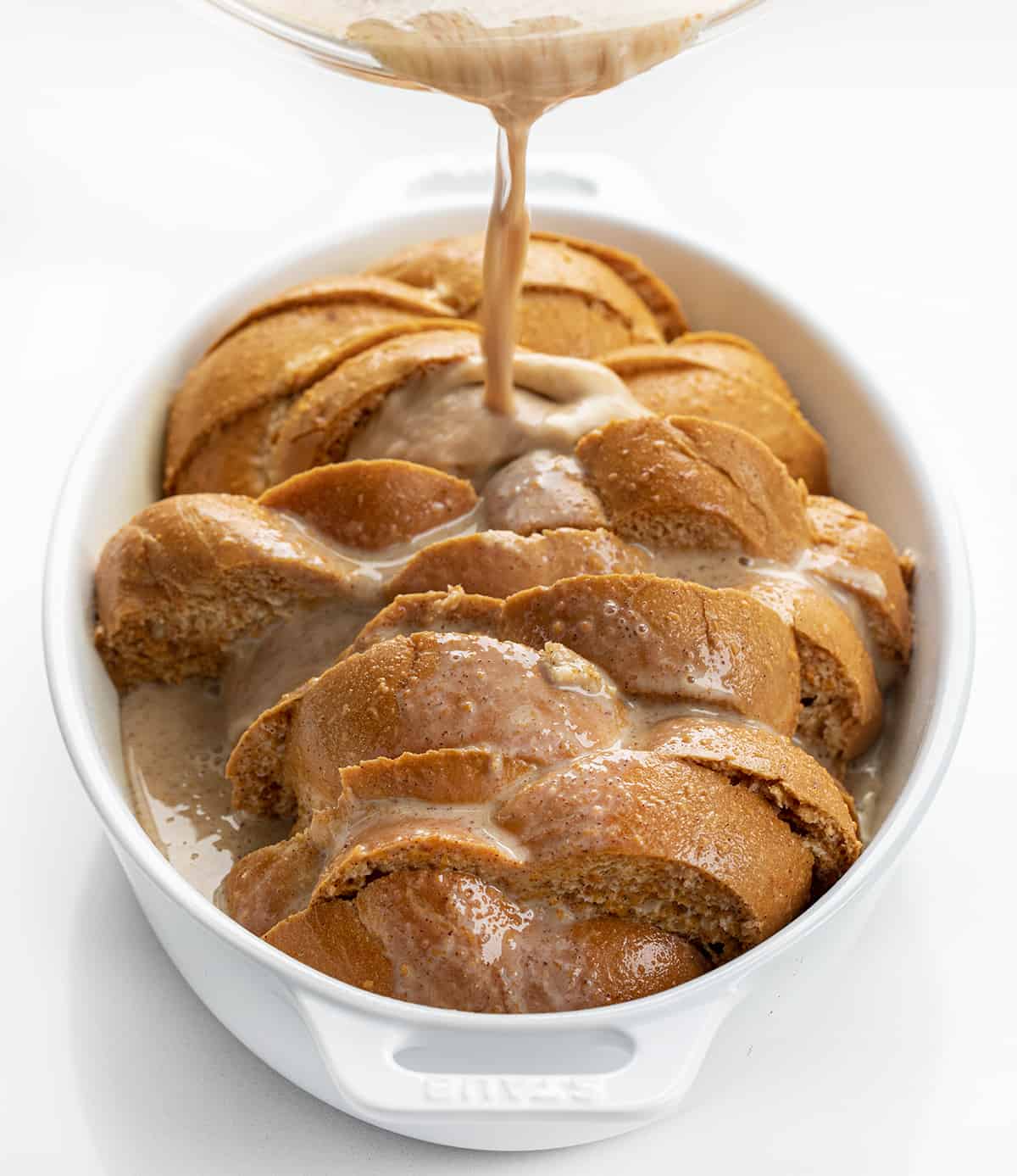 Pouring Egg Mixture Over Bread in Casserole Pan for Pumpkin French Toast Casserole.