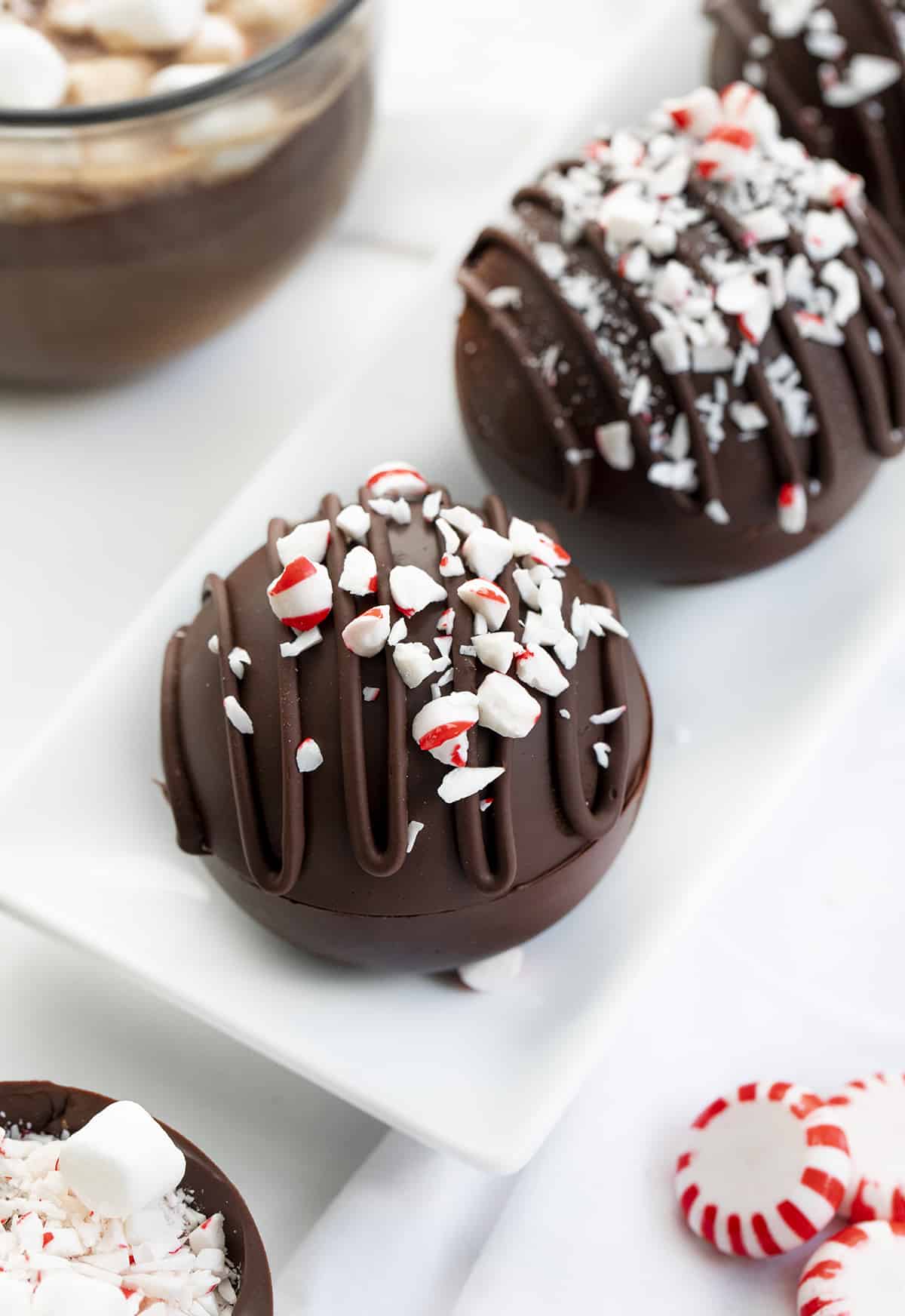 These Peppermint Hot Cocoa Bombs are not only amazingly delicious, but they are fantastic gift idea! With winter here, it’s time for hot drinks! It seems like peppermint also goes hand in hand with the coldest months of the year. When you add a bomb to a cup or mug of hot milk, it ‘explodes’, giving you a delicious cup of peppermint hot cocoa! Peppermint Hot Cocoa Bombs in a White Platter.