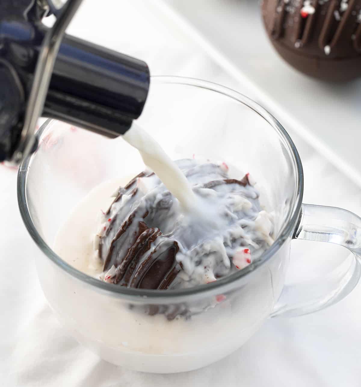 These Peppermint Hot Cocoa Bombs are not only amazingly delicious, but they are fantastic gift idea! With winter here, it’s time for hot drinks! It seems like peppermint also goes hand in hand with the coldest months of the year. When you add a bomb to a cup or mug of hot milk, it ‘explodes’, giving you a delicious cup of peppermint hot cocoa! Pouring Hot Milk of a Peppermint Cocoa Bombs.