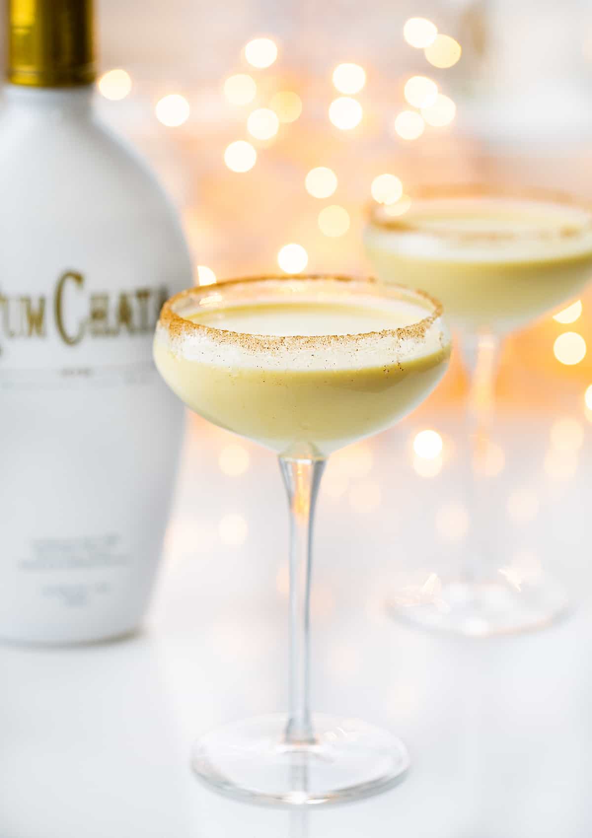 Rumchata Eggnog is an alcoholic beverage made with eggnog and RumChata® served in a glass with a cinnamon-sugar rim. It's the perfect cocktail to serve at your Christmas and New Year's Eve parties! Two Glasses of RumChata Eggnog with the RumChata Bottle.