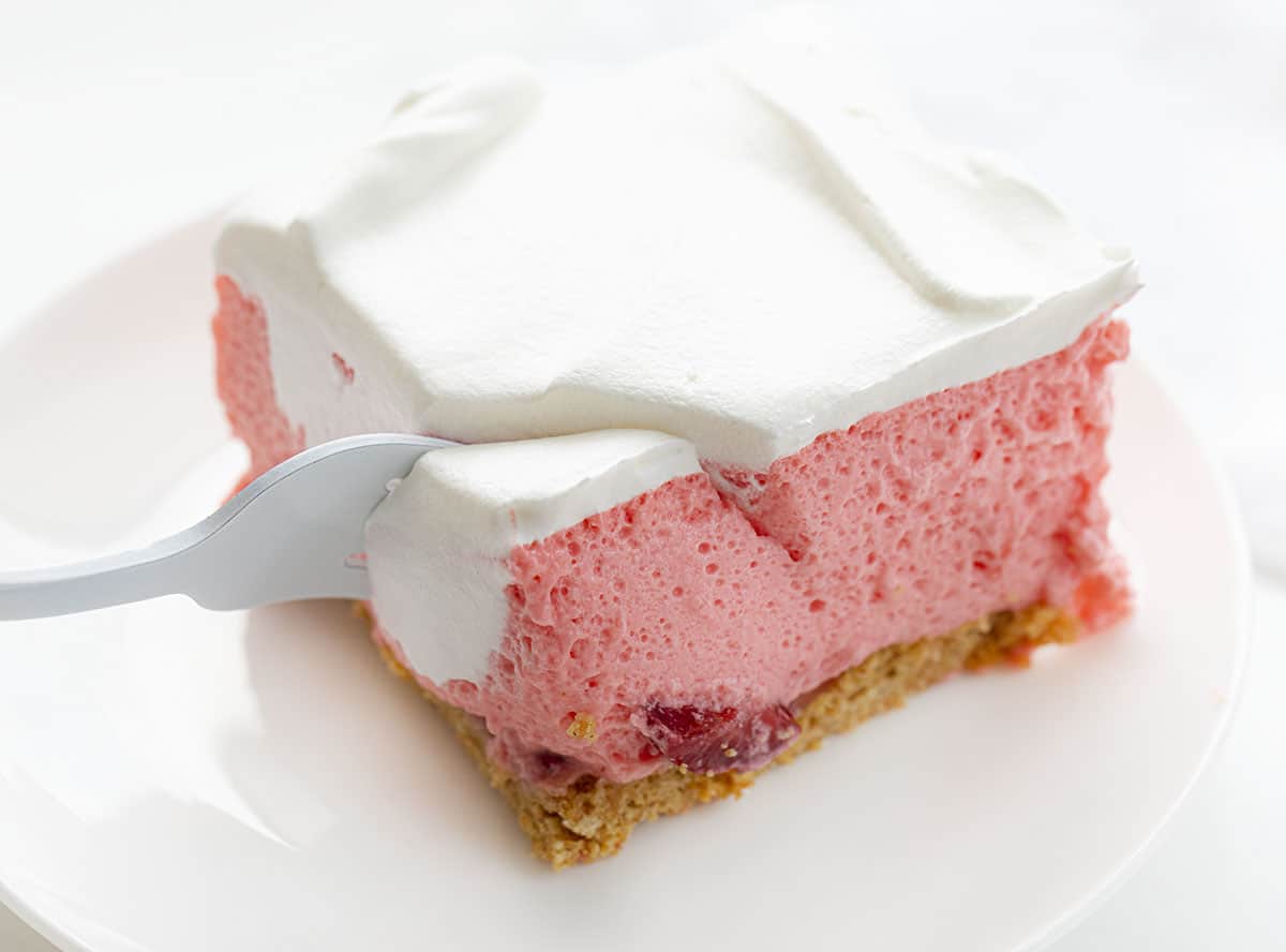 Strawberry Icebox Cheesecake is a light and fluffy no-bake dessert with fresh strawberries and a graham cracker crust. Strawberry Jello Cake, Woolworth Cake, Icebox Cake, Strawberry Woolworth Icebox Cake, Summer Cake, Refrigerator Cake, No Bake, Dessert, Strawberry Dessert, recipes, i am baker, iambaker Fork Taking Bite of Strawberry Icebox Cheesecake