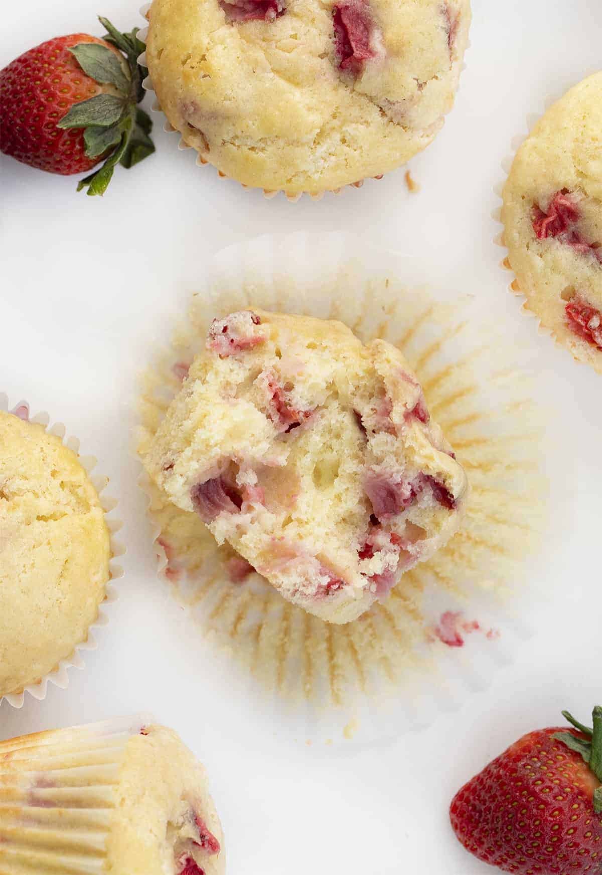 Strawberry Muffins are soft and fluffy muffins made with fresh strawberries for a perfectly sweet and refreshing treat. Muffins, Muffin Recipes, Breakfast, Strawberry Muffins, Real Strawberry Muffins, Baking, i am baker, iambaker, strawberry cupcake Overhead of Real Strawberry Muffins with One Halved to Show Inside