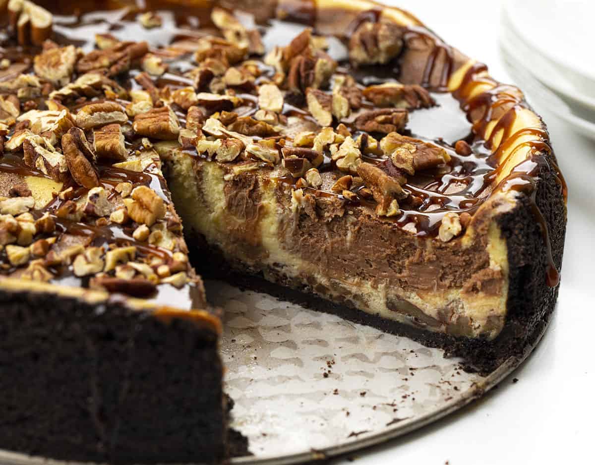Turtle Cheesecake is a dessert with an Oreo cookie and toasted pecans crust, filled with a chocolate-swirled cheesecake filling and topped with caramel, hot fudge, and more pecans. Cheesecake Recipe, Turtle Cheesecake, Chocolate Caramel Cheesecake, Easy Cheesecake, Ultimate Cheesecake, Holiday Desserts, Dessert, recipes, baking, i am baker, iambaker Cut Into Turtle Cheesecake